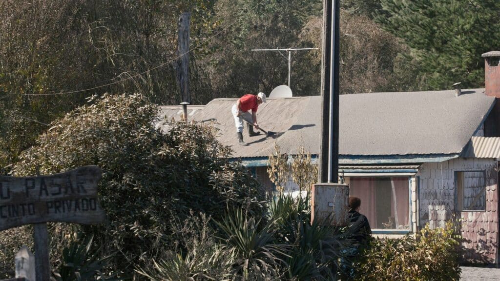 A person works on a roof in a rural setting.