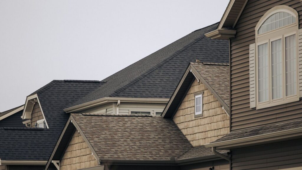 a row of houses with brown shingles and white windows
